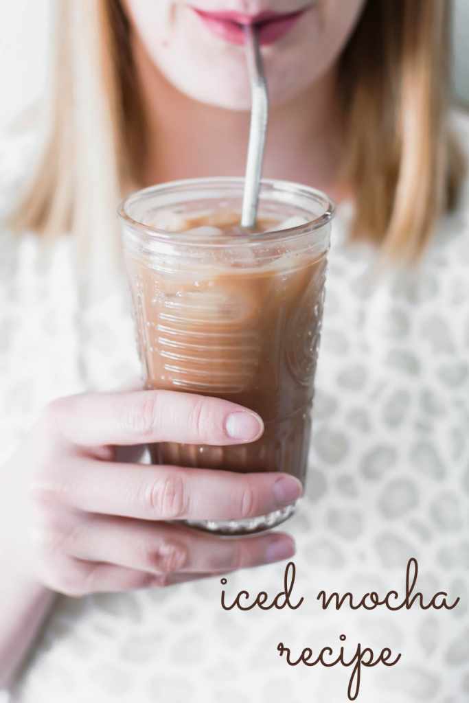 person taking a sip of homemade iced mocha recipe in a glass with a metal straw. Missing your favorite coffee shop? Try making a classic at home with this Iced Mocha Recipe. Only three ingredients required!