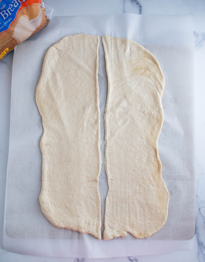 Bread dough rolled into a large rectangle and cut lengthwise into two equal pieces.