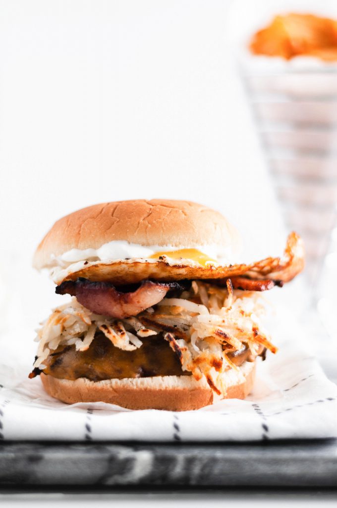 Make these Loaded Breakfast Burgers for dad this Father's Day. Juicy burgers topped with all the breakfast essentials, crispy hash browns, smoky bacon, drippy eggs and sharp cheddar cheese.