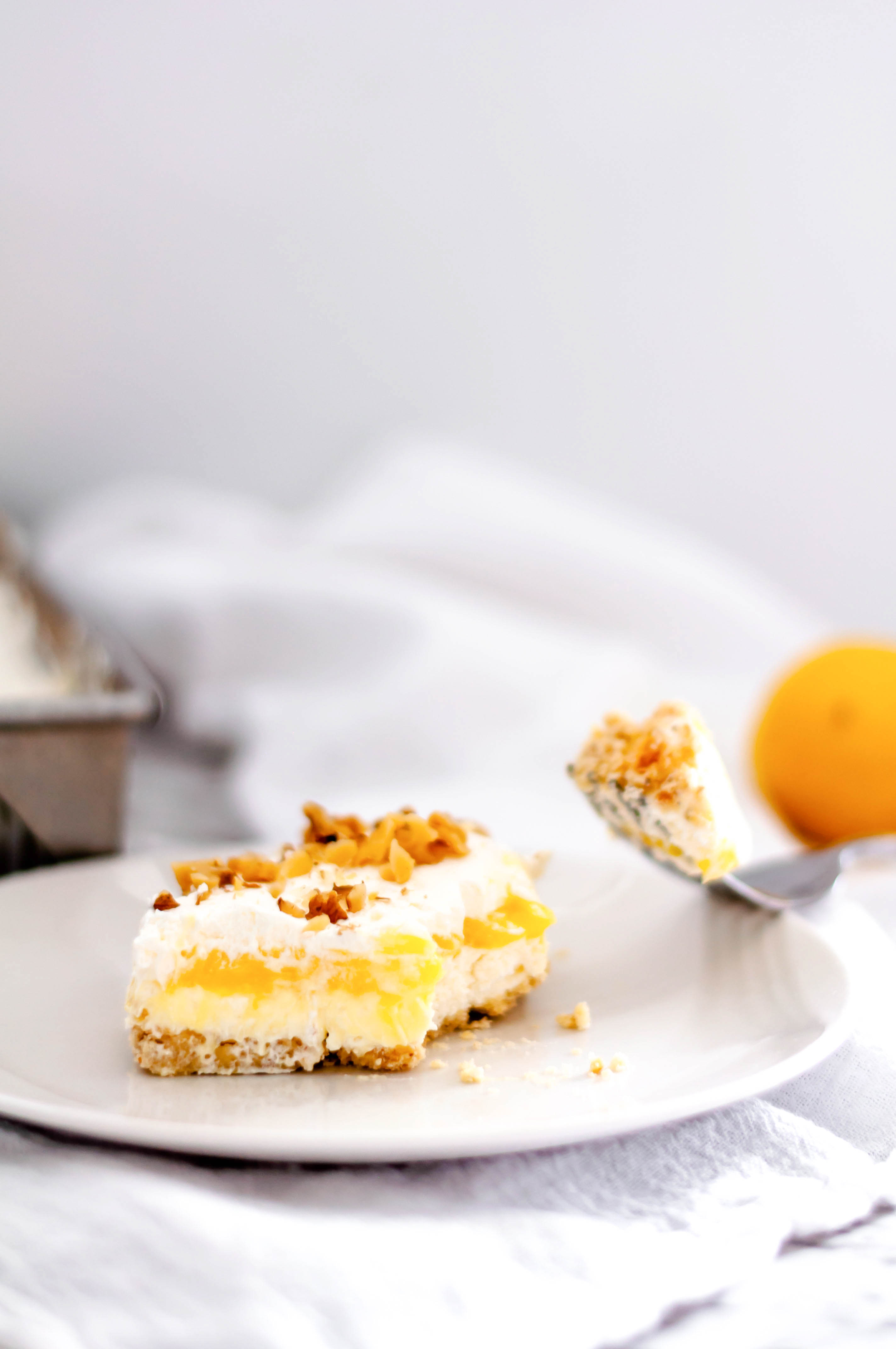 Lemon Hush is a delicious layered dessert of shortbread crust, cream cheese filling, lemon pudding, cool whip and chopped nuts. A family favorite.