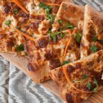 This Thai Chicken Pizza is packed with rich flavors. Whole wheat crust topped with a peanut sauce, shredded chicken and cheese. Top with shredded carrots and cilantro after baking.