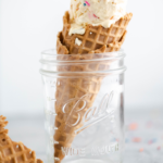 Waffle cone filled with cake batter ice cream resting in a mason jar.