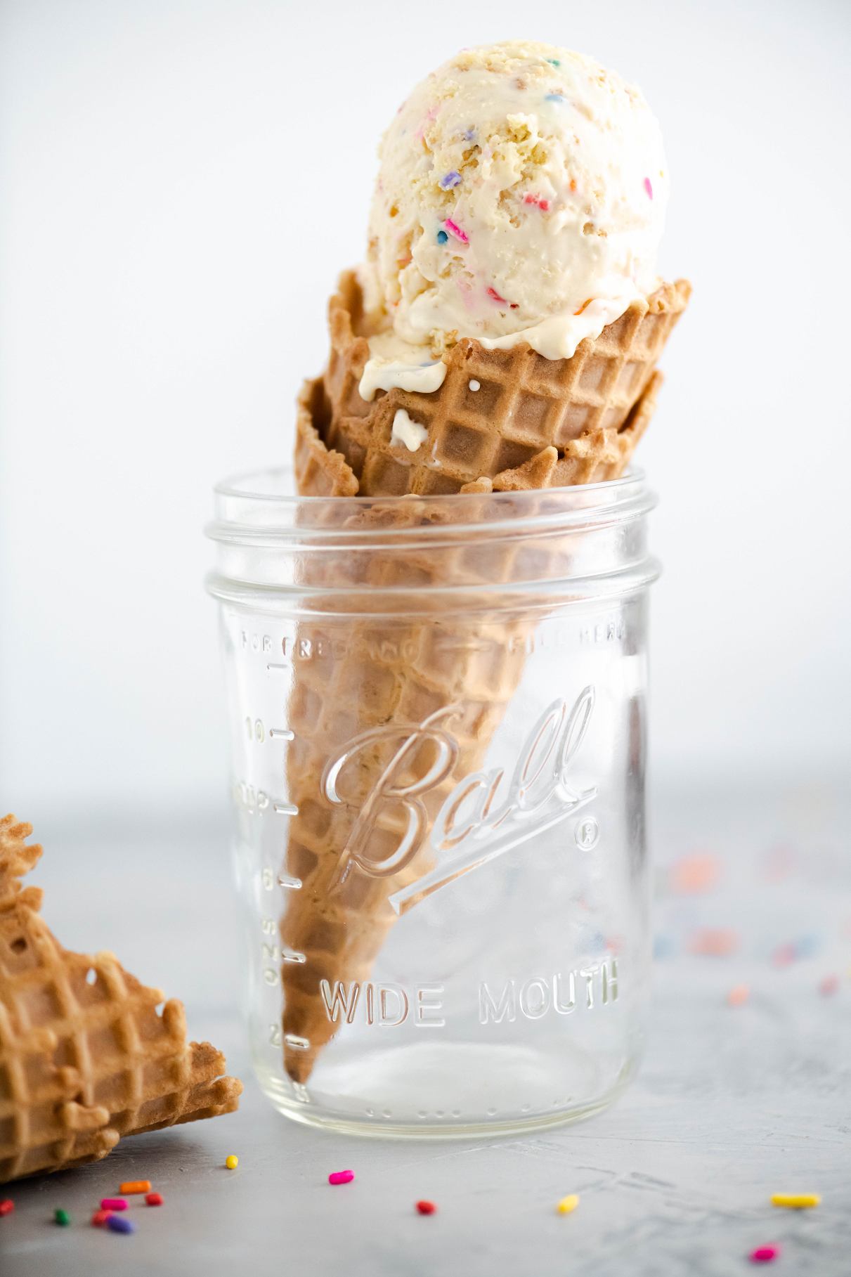Waffle cone filled with cake batter ice cream resting in a mason jar.