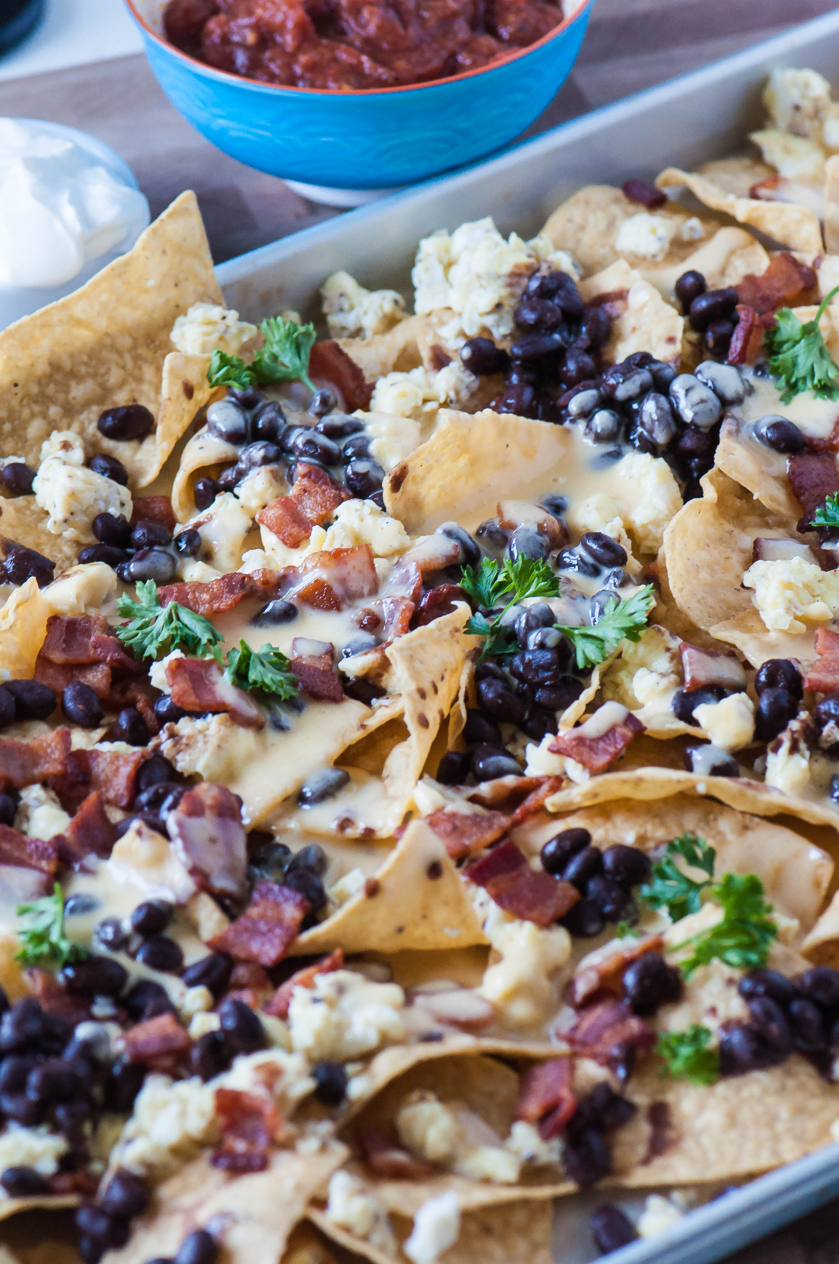 Breakfast Nachos are packed full of scrambled eggs, crispy bacon, black beans and a creamy cheese sauce.