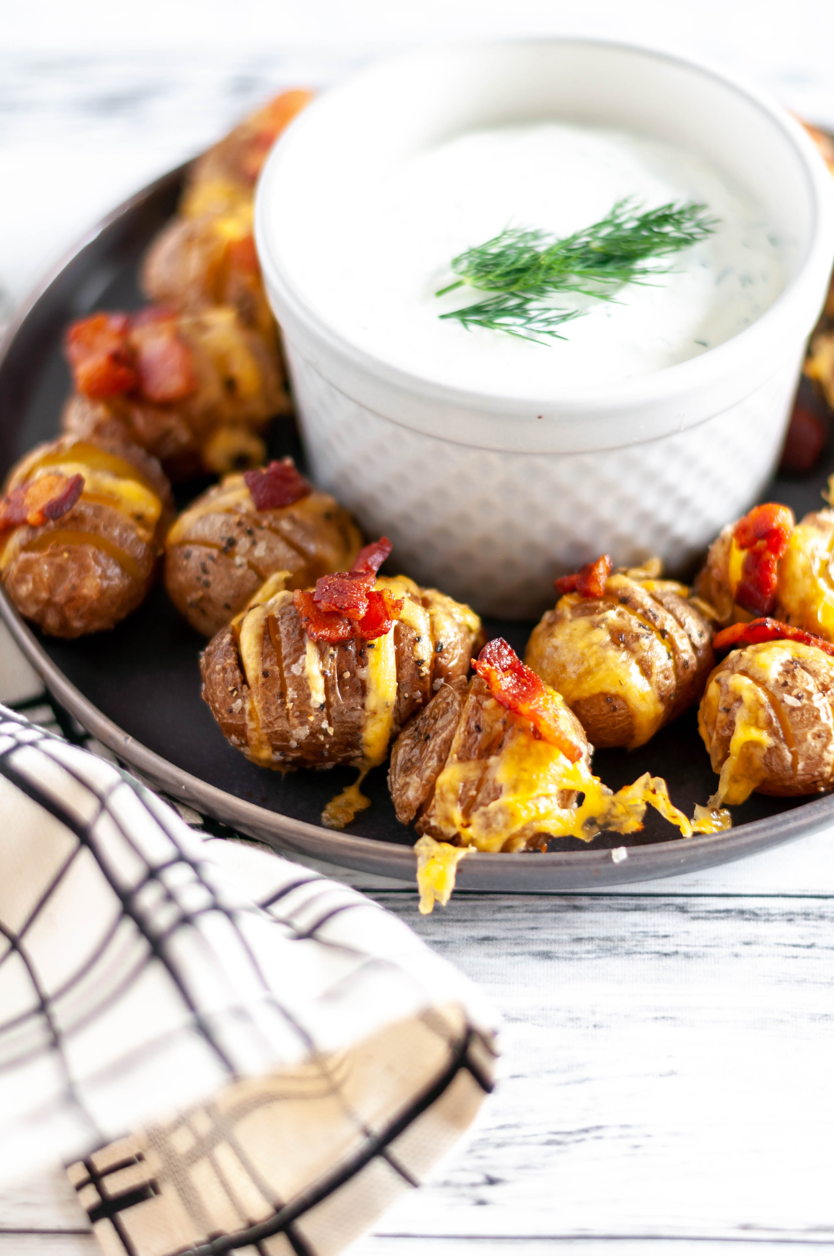 Loaded Mini Hasselback Potatoes are a delicious and adorable party appetizer your holiday needs. Serve with this simple, fresh dill sour cream.