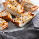 This Ultimate Cheesy Garlic Bread is the perfect addition to dinner tonight. Buttery garlic bread smothered in three cheeses and Italian seasoning.