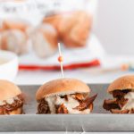 It's football season and that means we need all the delicious party food. Start the game off right with these Cheesy Pulled Pork Sliders. Slow cooker pulled pork, barbecue sauce and a rich, cheesy sauce all loaded atop a soft, pillowy Rhodes Warm-N-Serv roll.