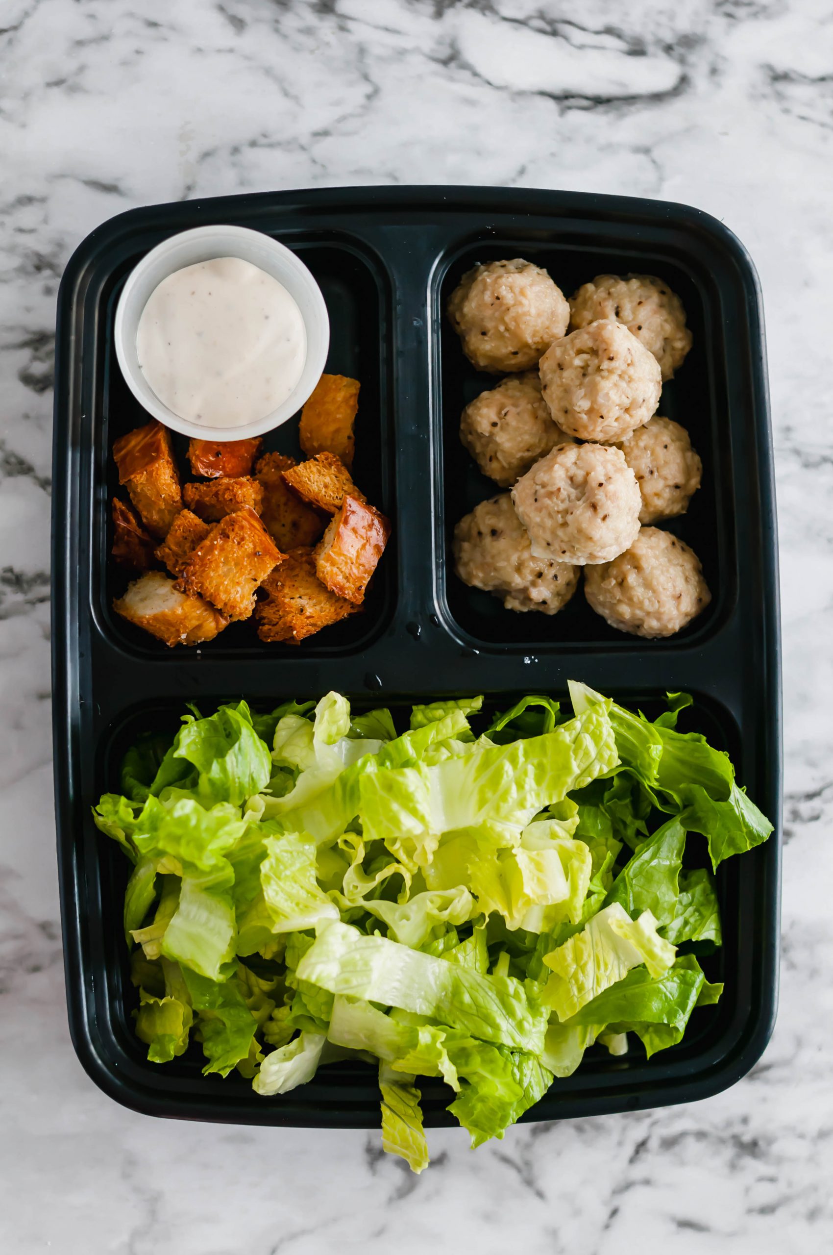 Salad Meal Prep is the perfect way to start out your New Year healthy. 45 minutes of prep results in a weeks worth of healthy and delicious lunches. Caesar dressing, homemade croutons and mini chicken meatballs add lots of flavor to the mix.