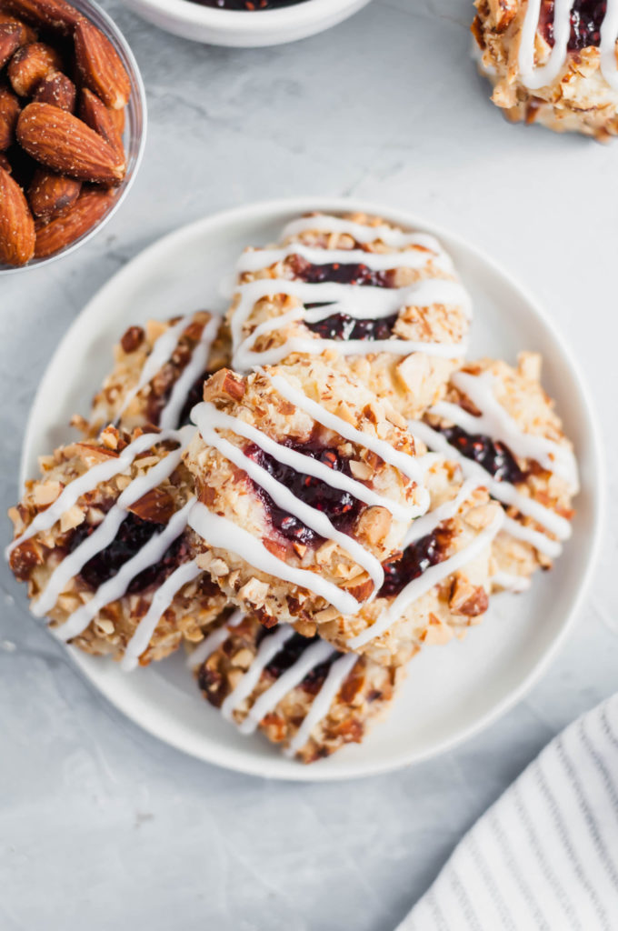 These Raspberry Thumbprint Cookies will quickly become your favorite Christmas cookie. Melt in your mouth cookies, rolled in chopped salted almonds, filled with raspberry jam and drizzled with glaze. The prettiest cookie to add to your Christmas cooking baking list