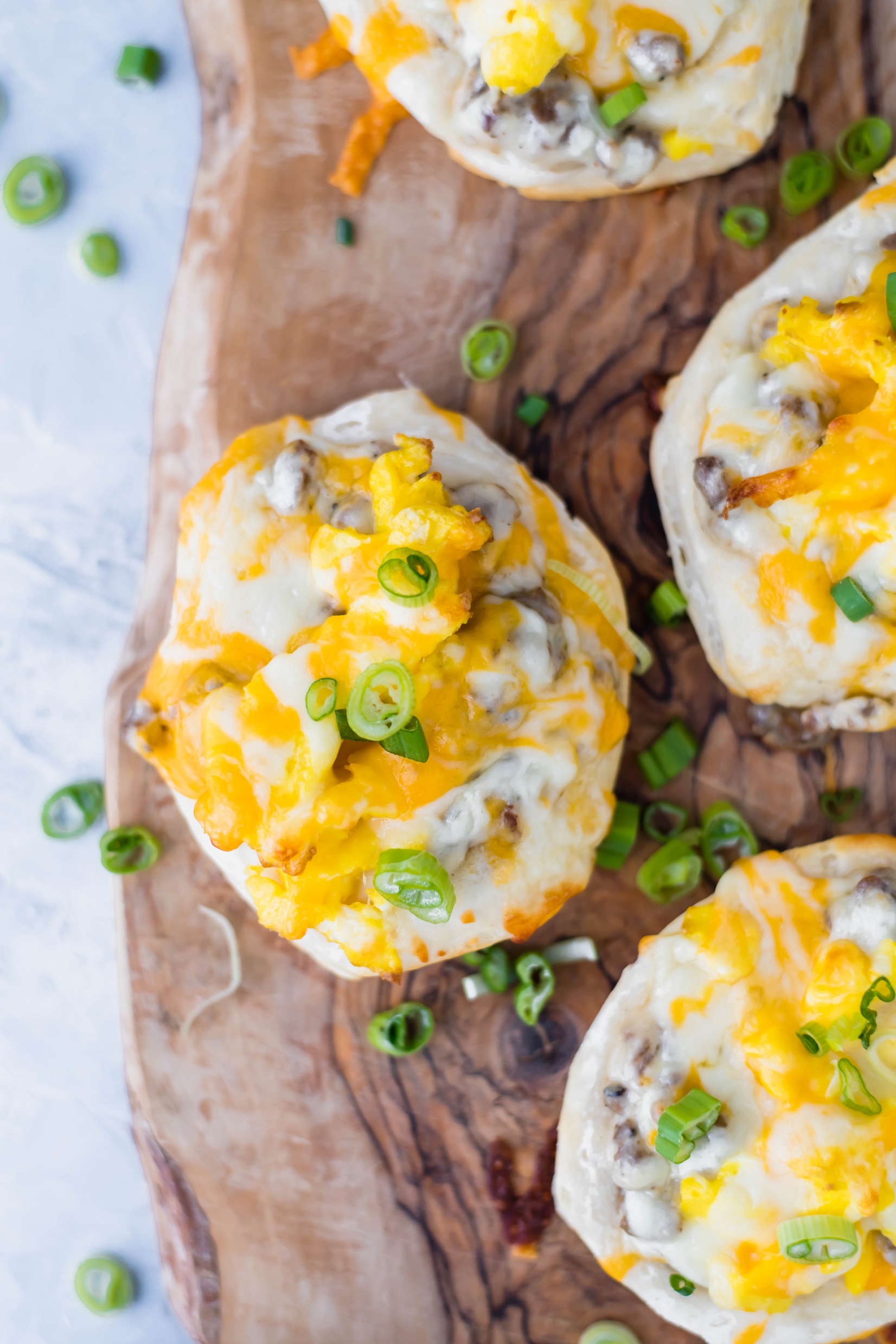 Looking for a delicious breakfast or fun dinner? These Mini Breakfast Pizzas start with a store-bought biscuit crust, topped with a simple sausage gravy, fluffy scrambled eggs and cheese.