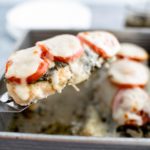 Baked pesto chicken being lifted from baking dish on a small spatula.