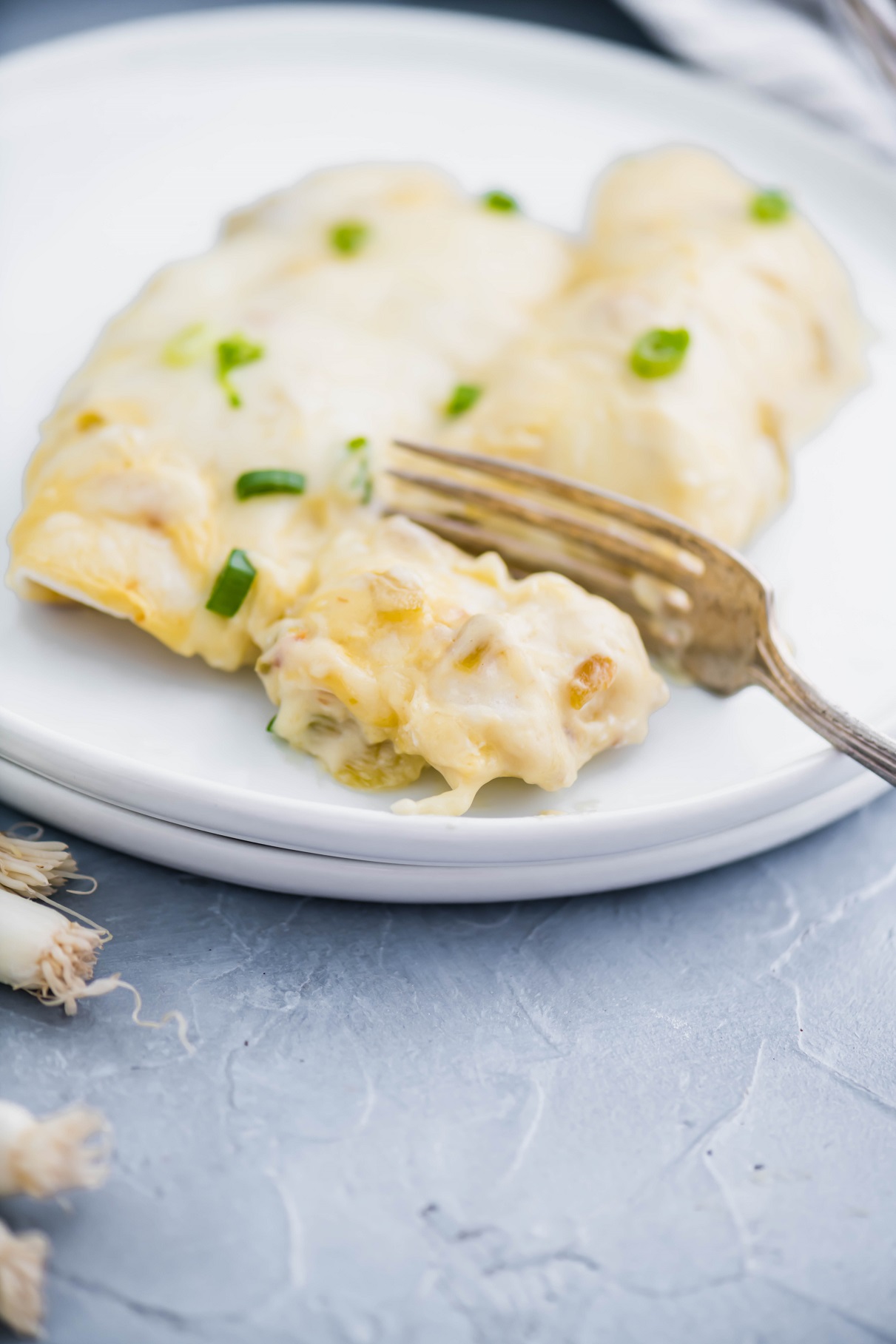 Plate of cream cheese chicken enchiladas with a fork cutting a bite.