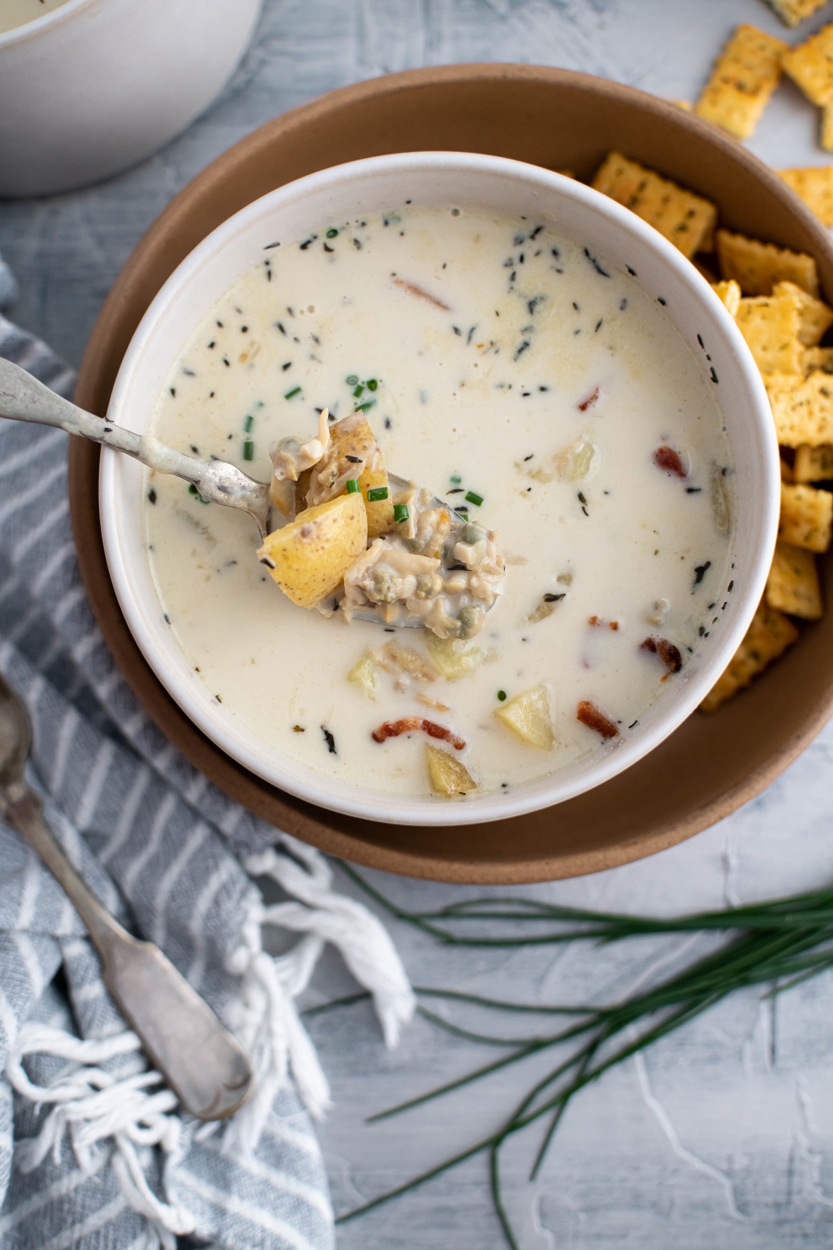 Bowl of clam chowder with spoon lifting out soup to see texture.