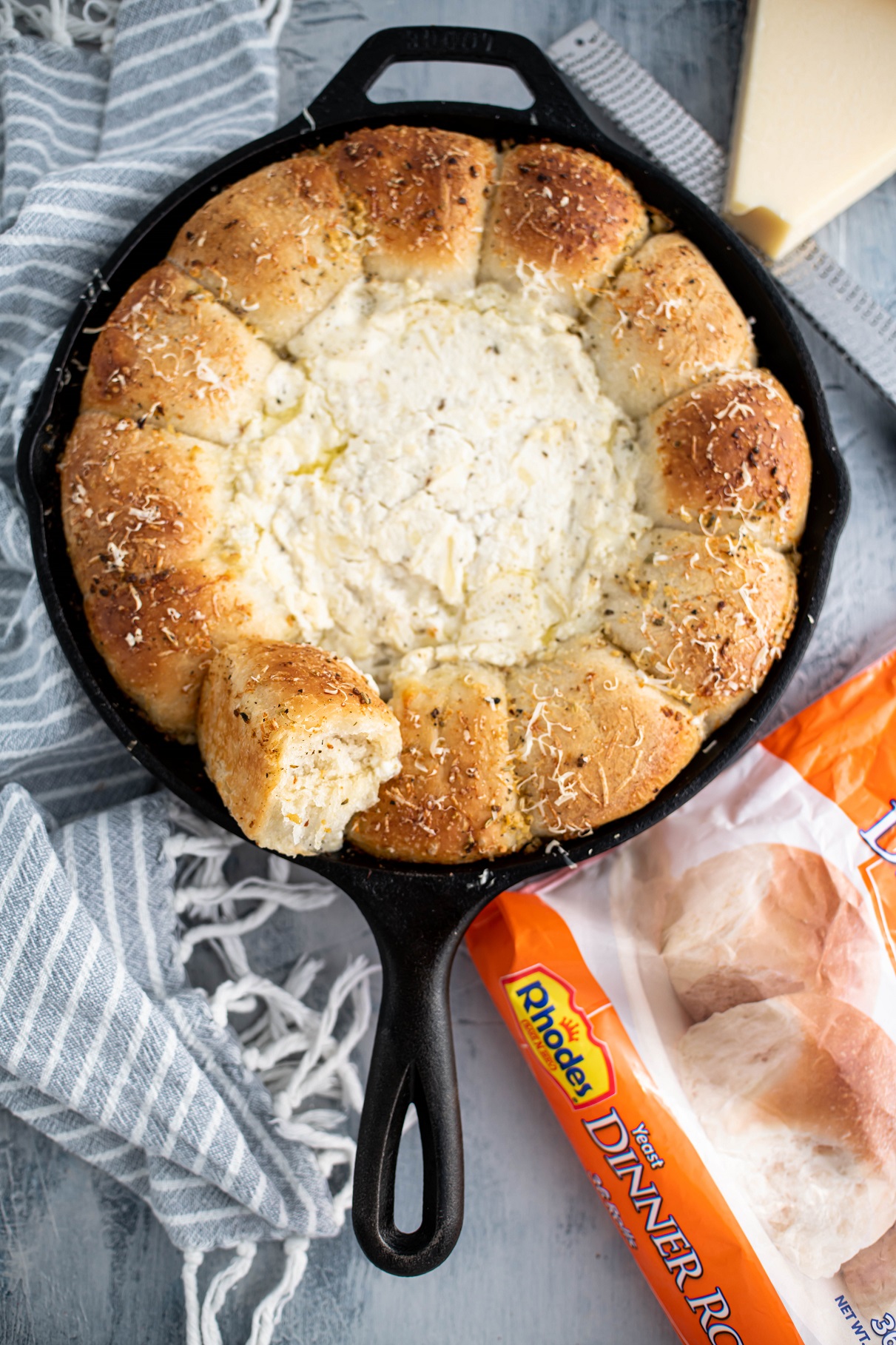Cast iron skillet with rolls around the exterior and white pizza dip in the center.