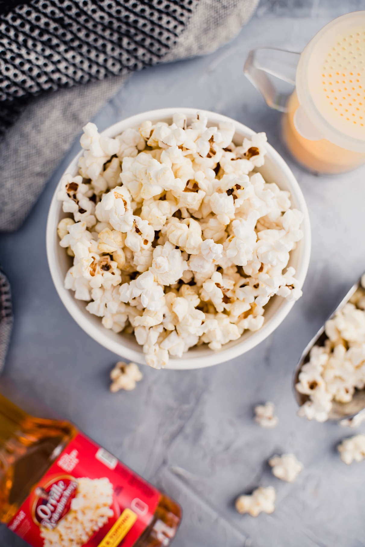 Bowl of Instant Pot Popcorn with a metal scoop of popcorn to the side and shaker of salt.