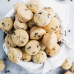 Bowl lined with a white and gray striped towel piled high with mini chocolate chip muffins.
