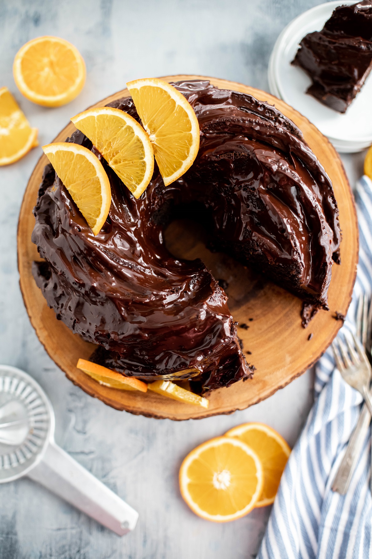 Orange Chocolate Bundt Cake on a wooden cake stand with a slice cut out and on a plate in the background.
