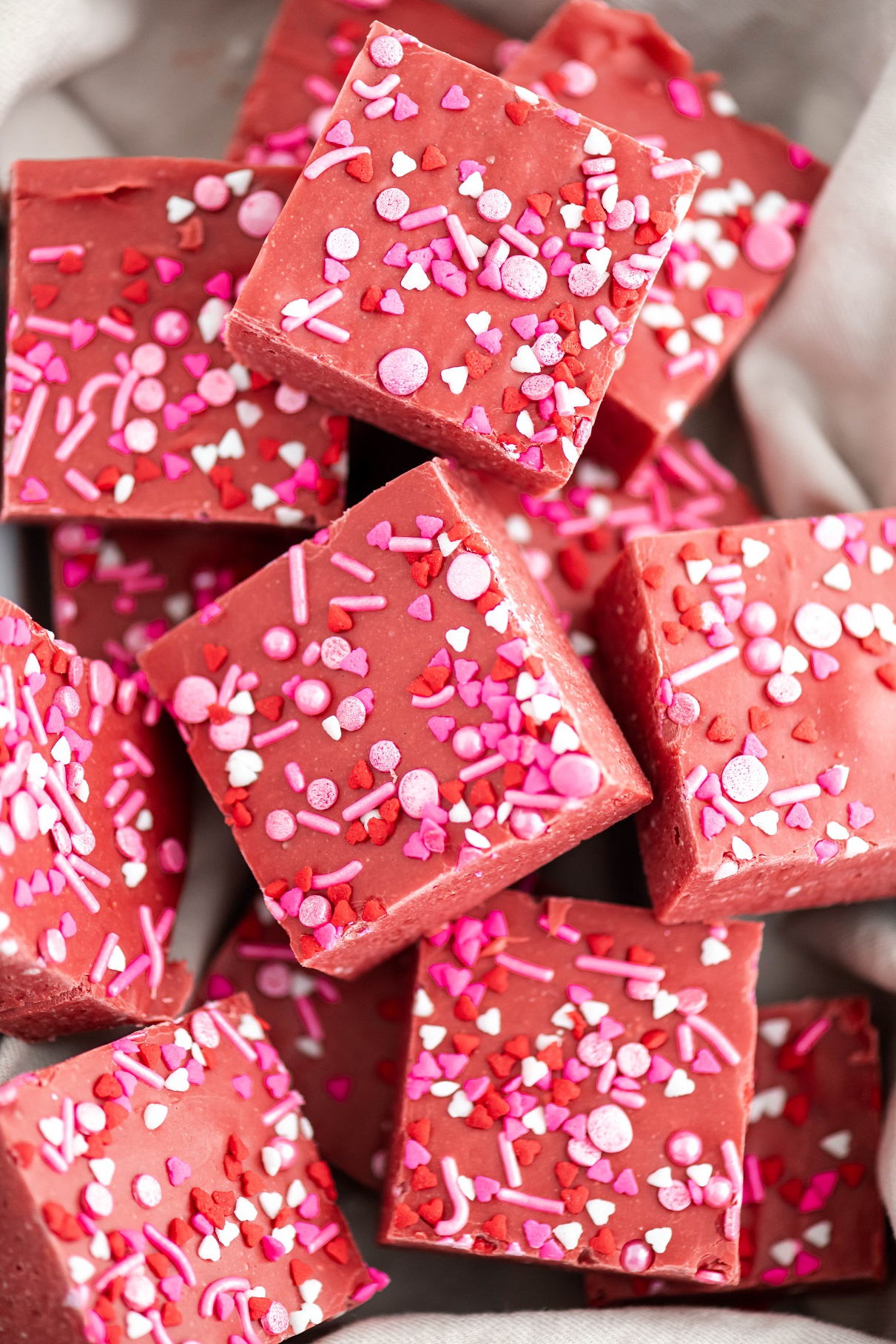 Close up of red velvet fudge piled into a dish lined with a pale pink cloth napkin.