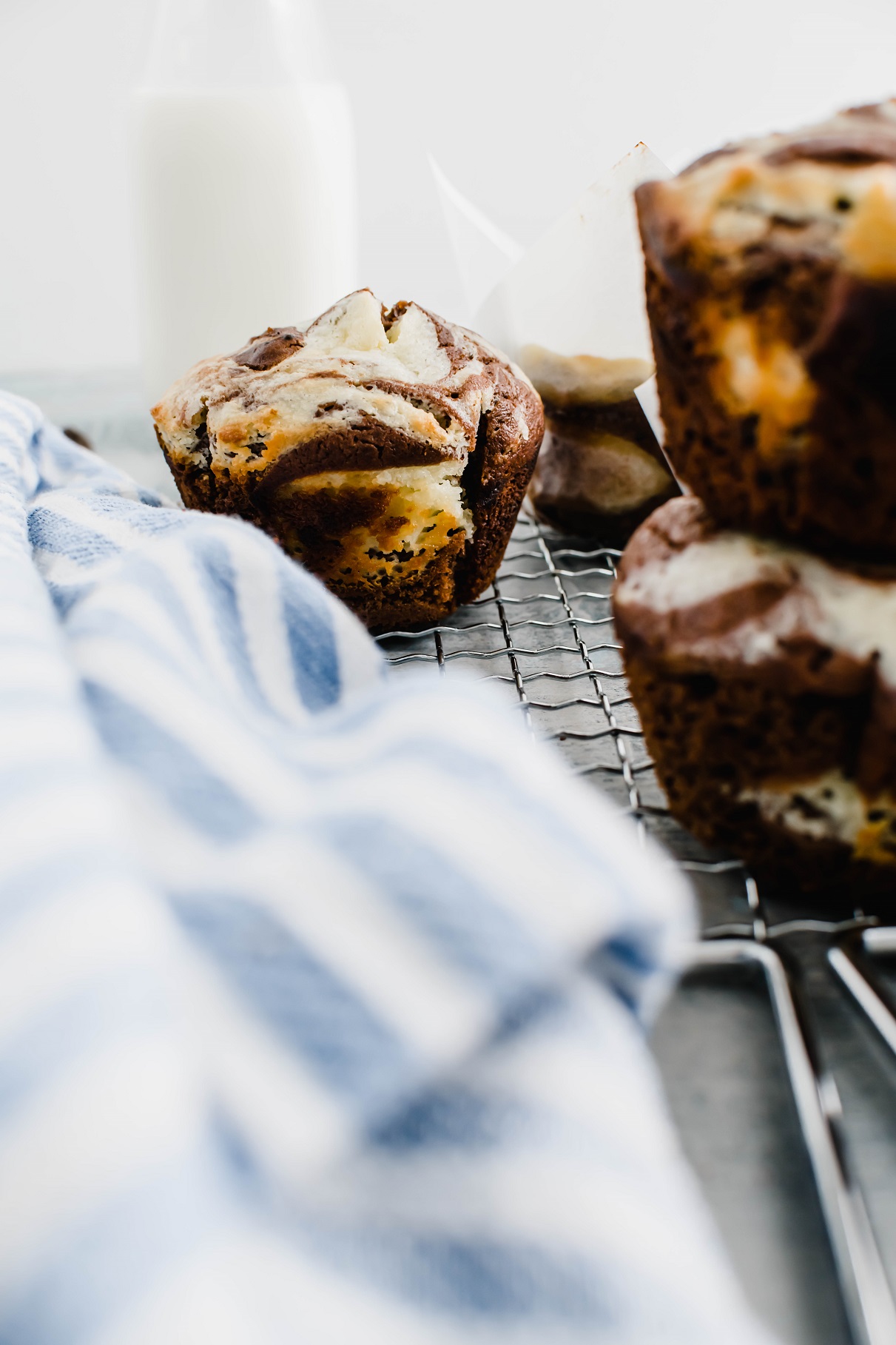 Chocolate cream cheese muffins stacked in a pile in the forefront of the photo another in the background that is the focus.