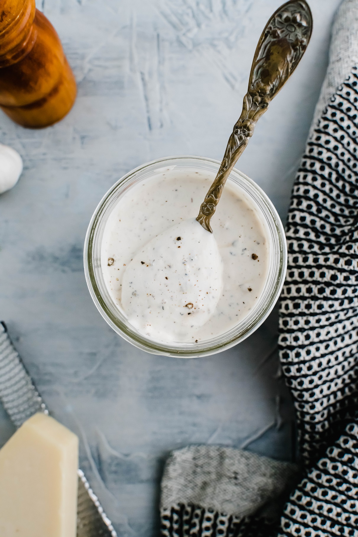 Parmesan peppercorn dressing in a wide mouth mason jar. Spoon in the jar slightly lifting a spoonful.