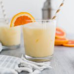 Two cocktail glasses filled with creamsicle cocktail with an orange slice garnish.