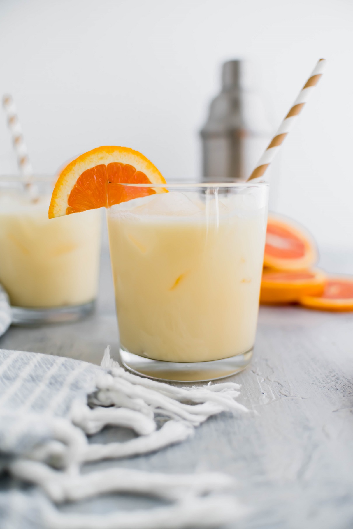 Two cocktail glasses filled with creamsicle cocktail with an orange slice garnish.