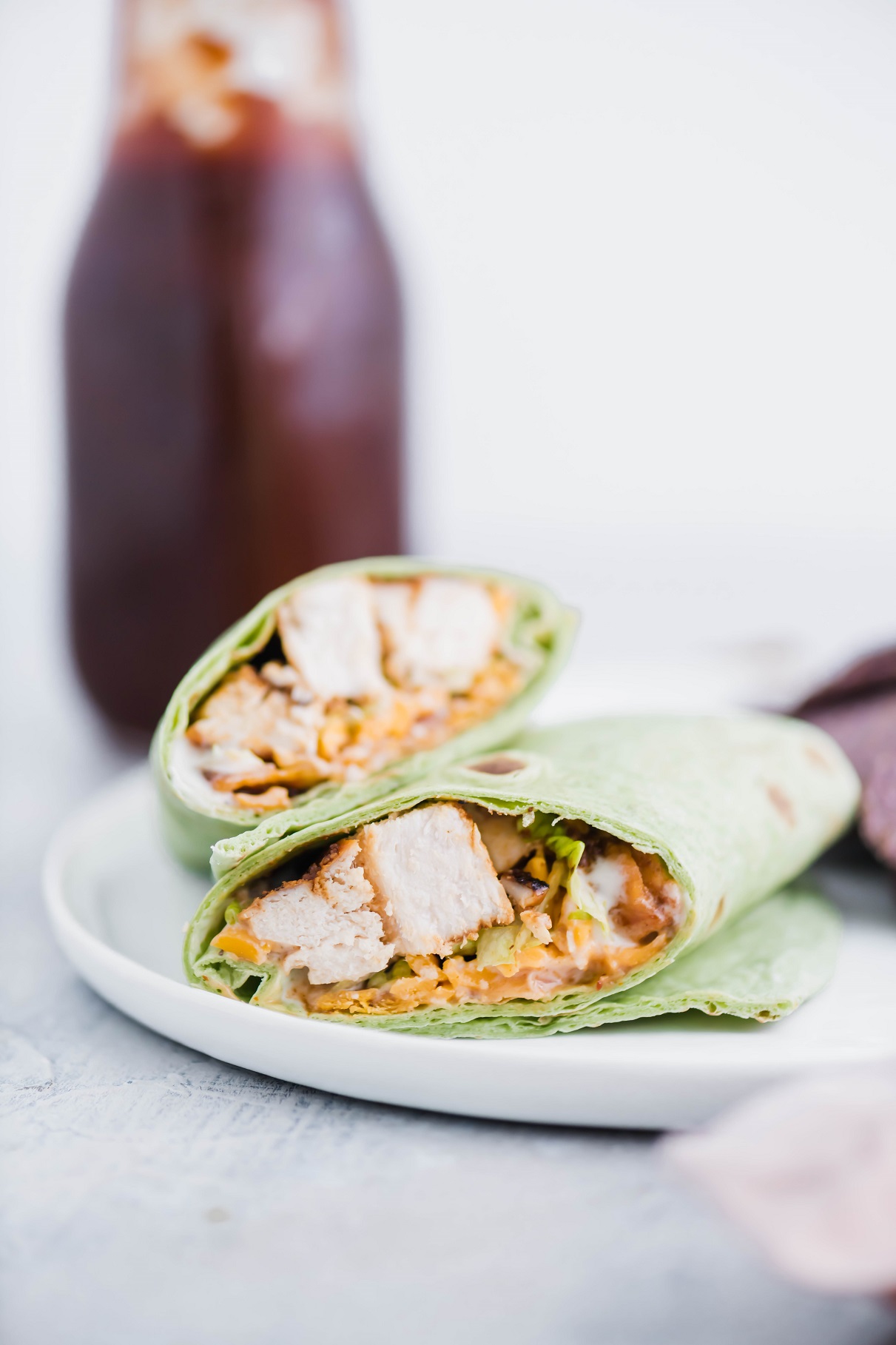BBQ Chicken Wrap sliced on the diagonal on a white plate with blue corn toritlla chips.