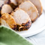 Slices of pork tenderloin on a white round plate.