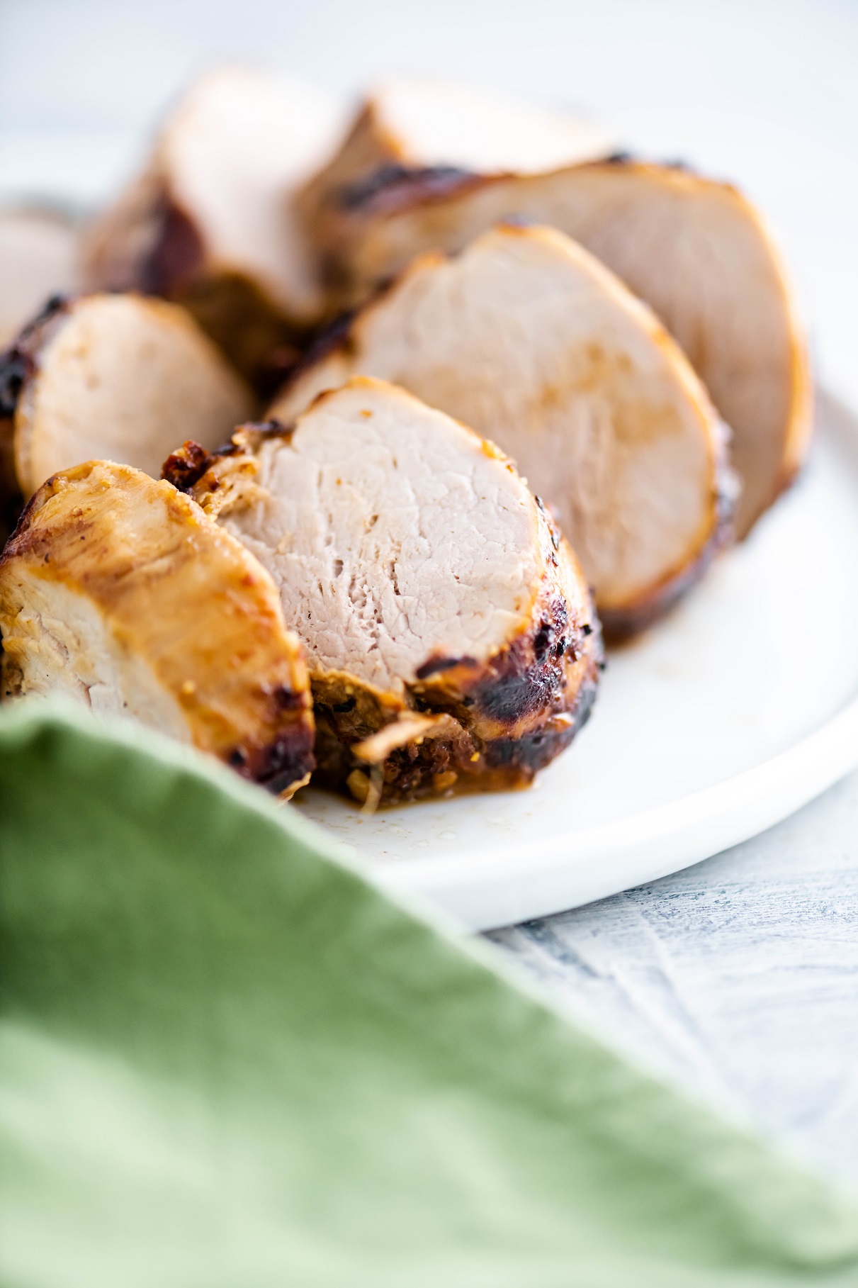 Slices of pork tenderloin on a white round plate.