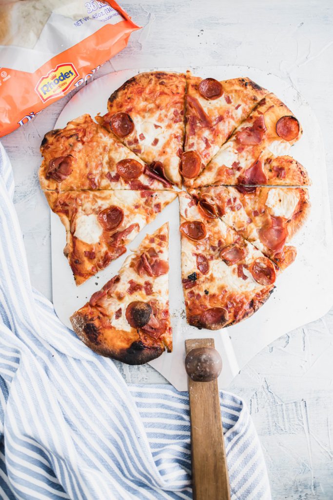 Sliced wood fired pizza on a pizza peel.