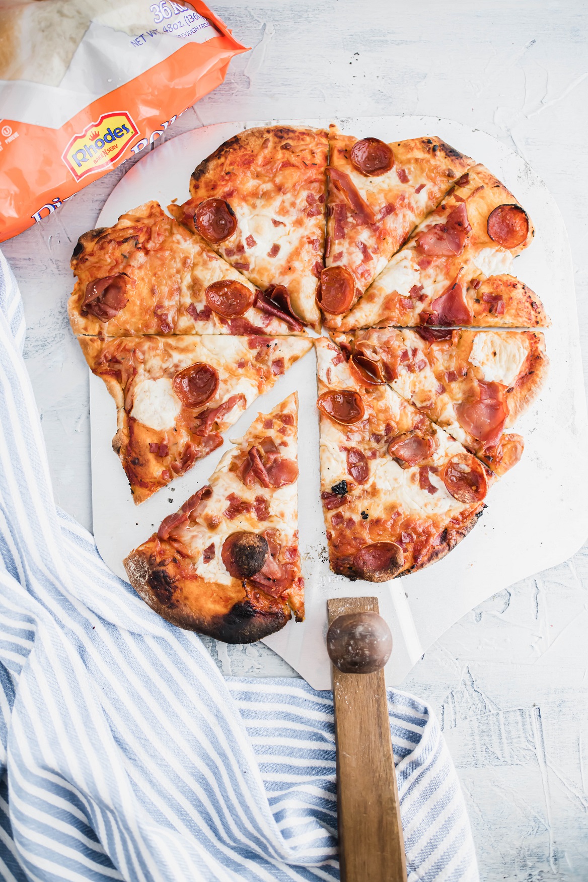 Sliced wood fired pizza on a pizza peel.