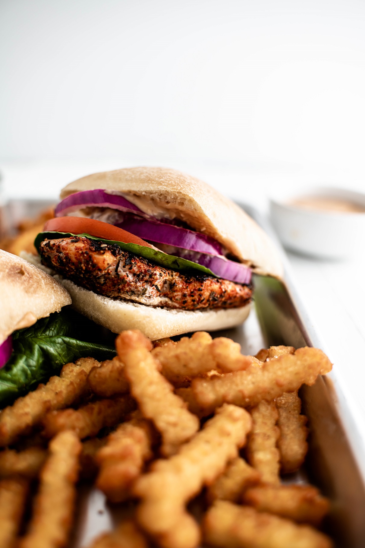 chicken sandwich on a platter with fries.