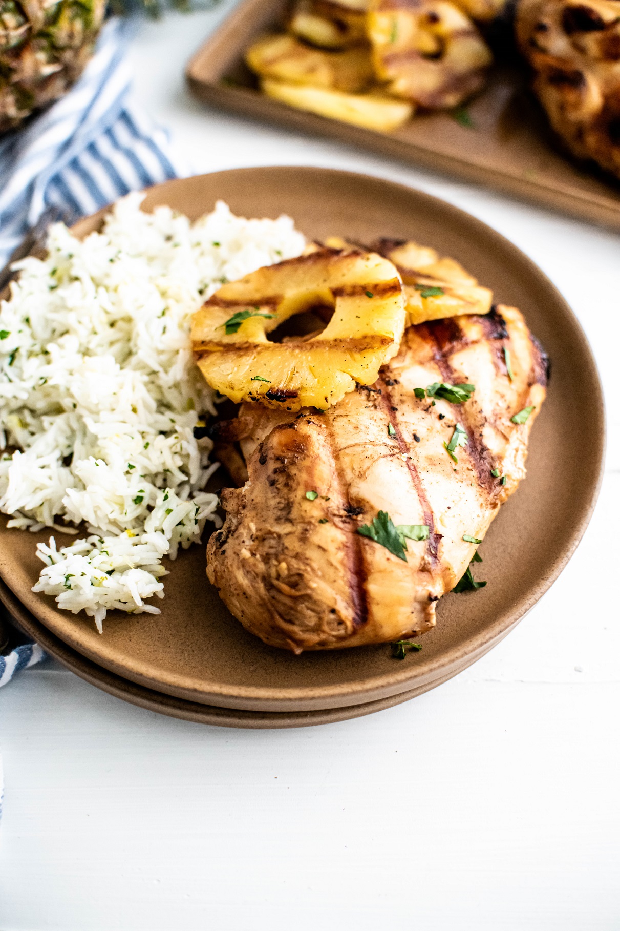 Grilled pineapple chicken and grilled pinapple rings on a plate with cilantro lime rice on the side.