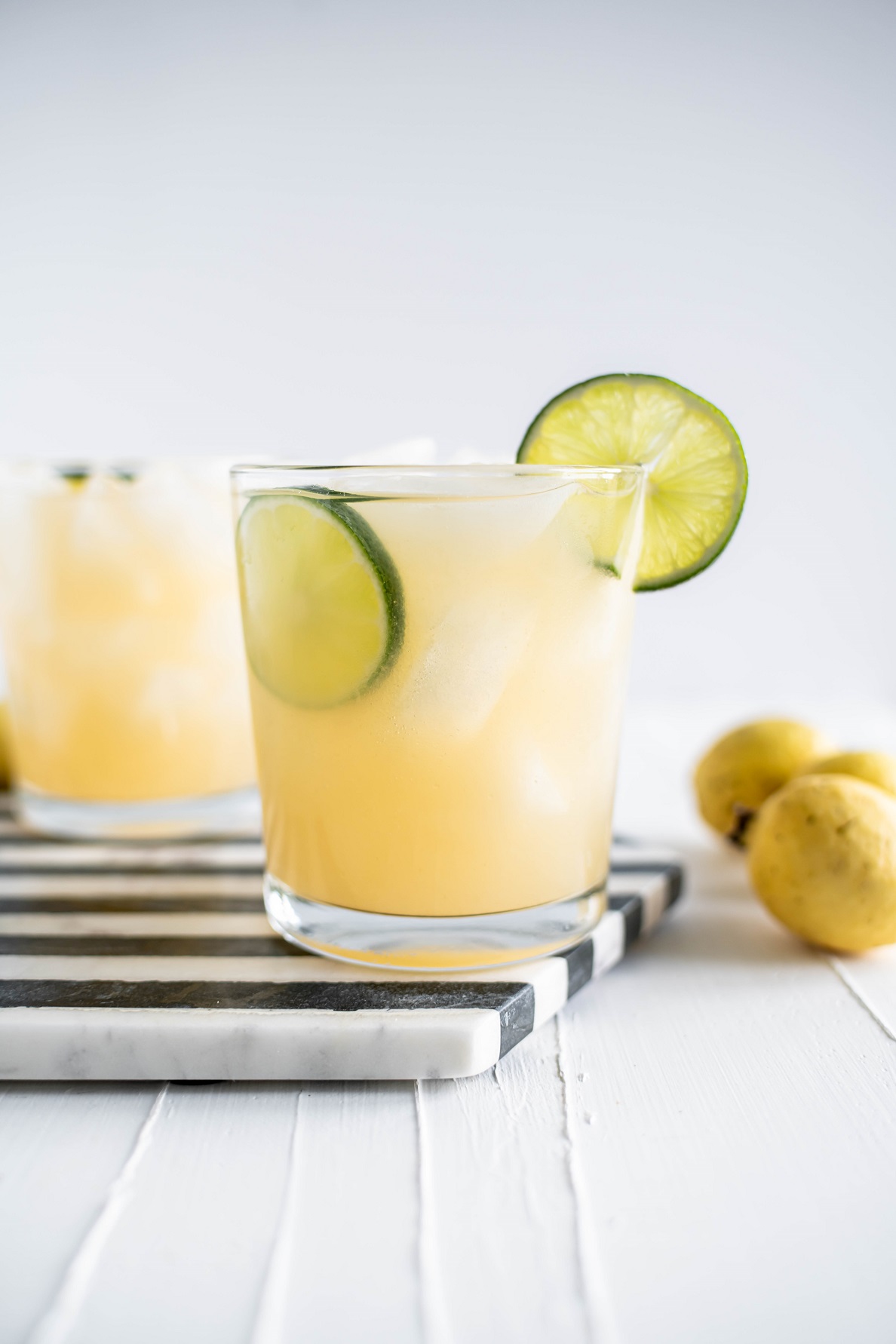 Two guava margaritas on a black and white striped hexagon marble board.