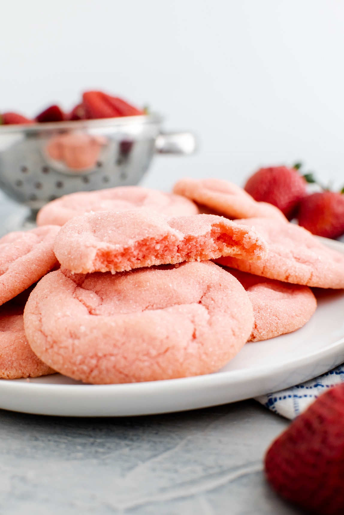 Plate of strawberry sugar cookies. One broken in half to show the pretty pink color inside.