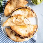 4 tacos on a round white plate.