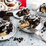 Three small white round plates with a cookies and cream cinnamon roll on each. Rhodes packaging in the background.