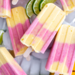 Layer of ice cubes topped with strawberry mango popsicles. Garnish of lime slices and half a mango.