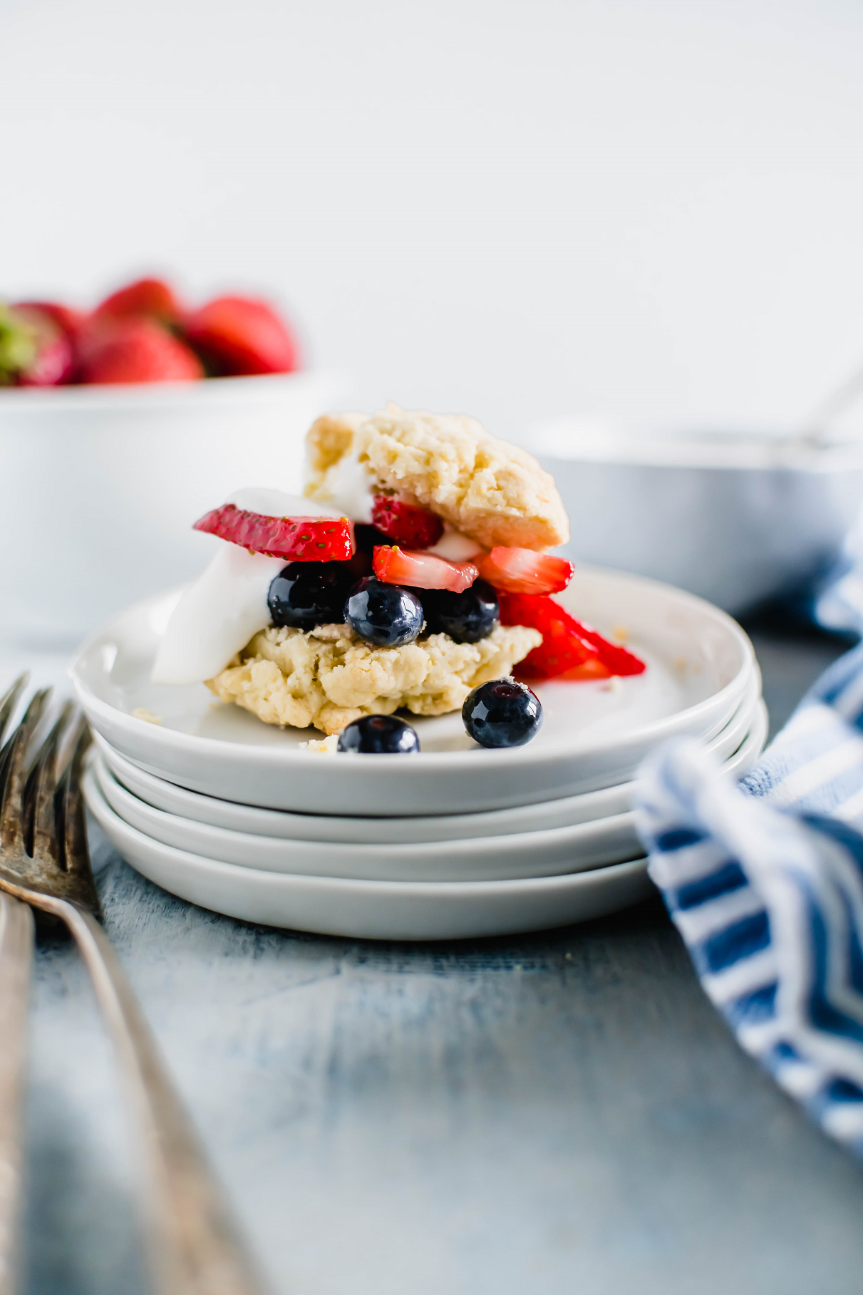 Shortcake fille with blueberries and strawberries and a dollop of whipped cream. Bowl of strawberries in the background.