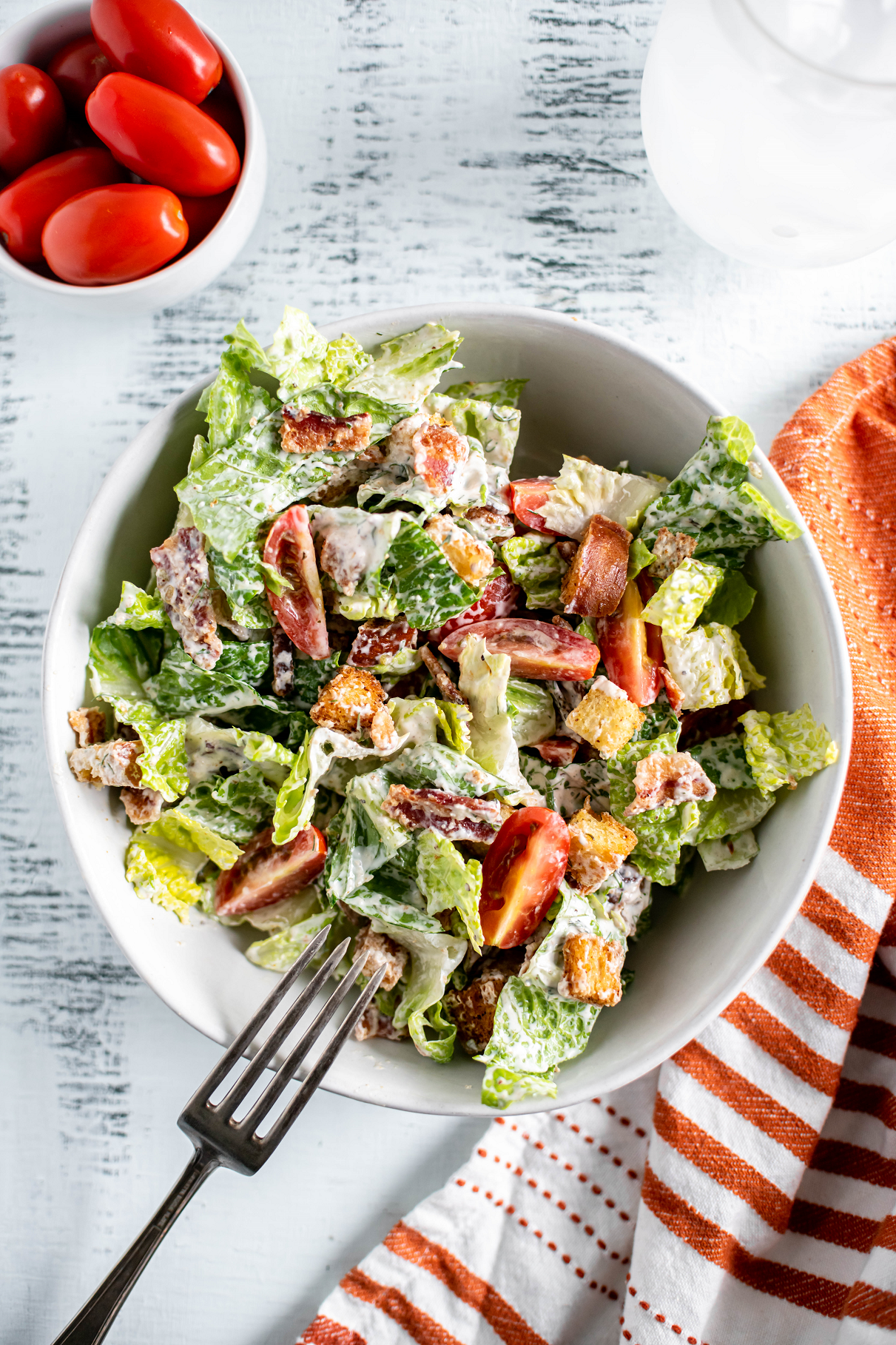 Bowl filled with blt salad. Fork leaning on the edge of the bowl.