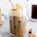 Close up of salted caramel cold brew in a glass with a metal straw.