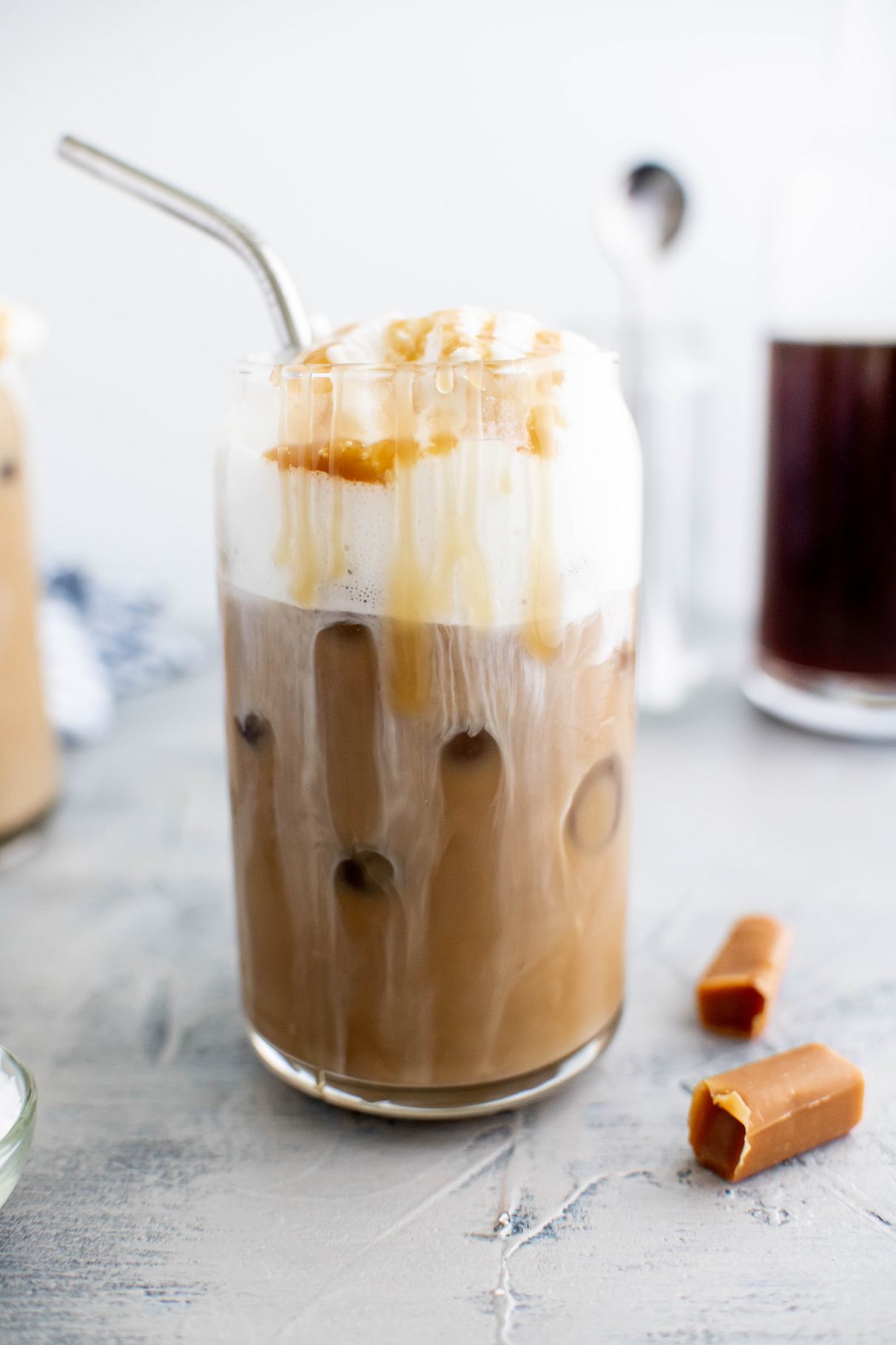 Close up of salted caramel cold brew in a glass with a metal straw.