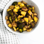 White round bowl filled with roasted potatoes and broccoli.
