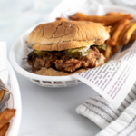 Fried chicken sandwich in a basket with fries.