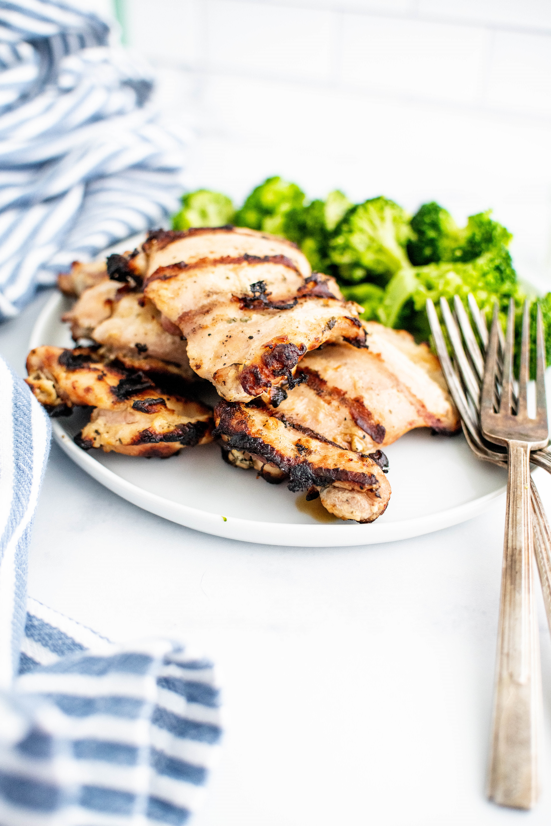 Grilled ranch chicken on a round white plate with steamed broccoli.