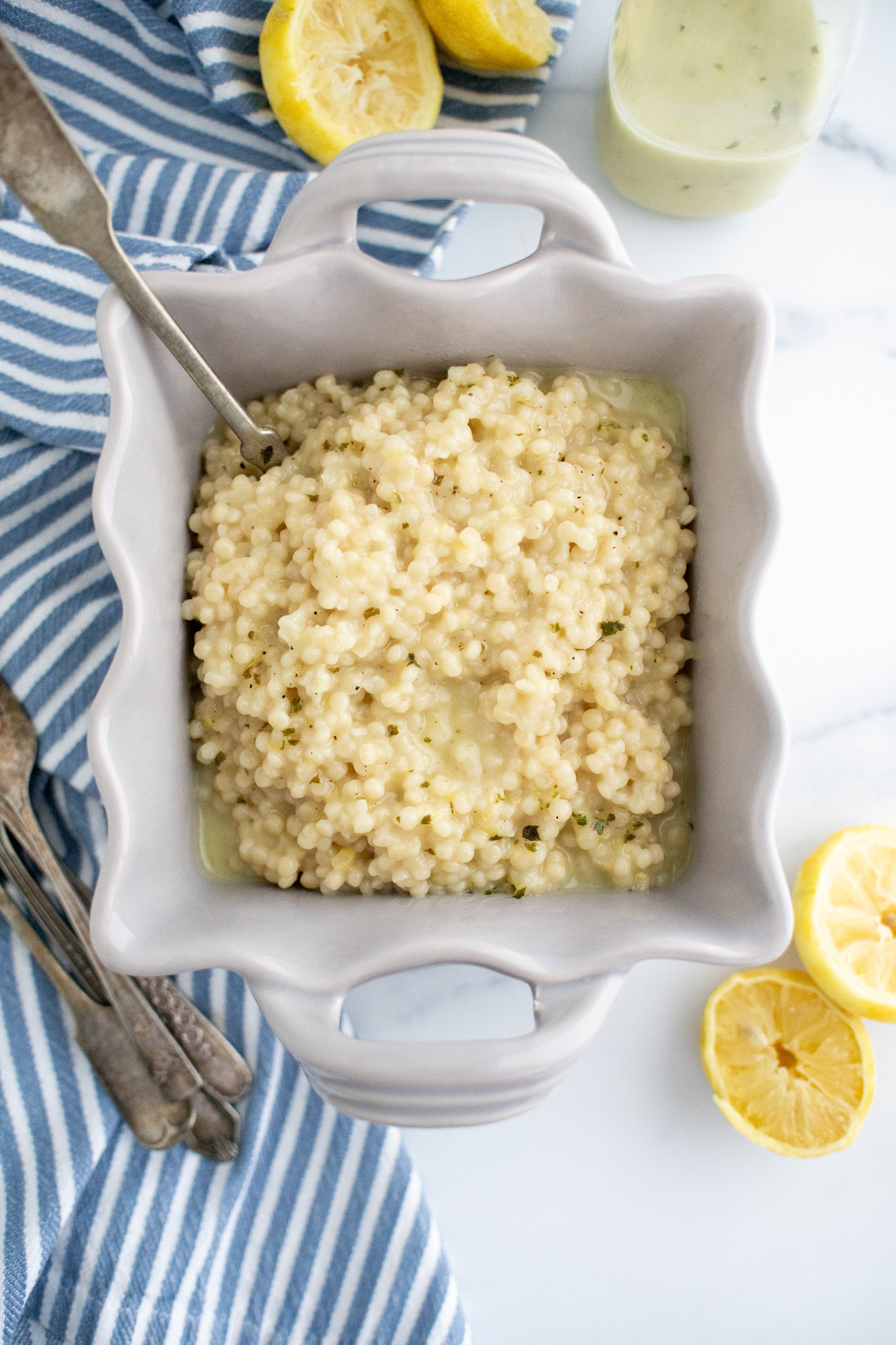 Square dish filled witth lemon couscous drizzled with lemon herb vinaigrette.