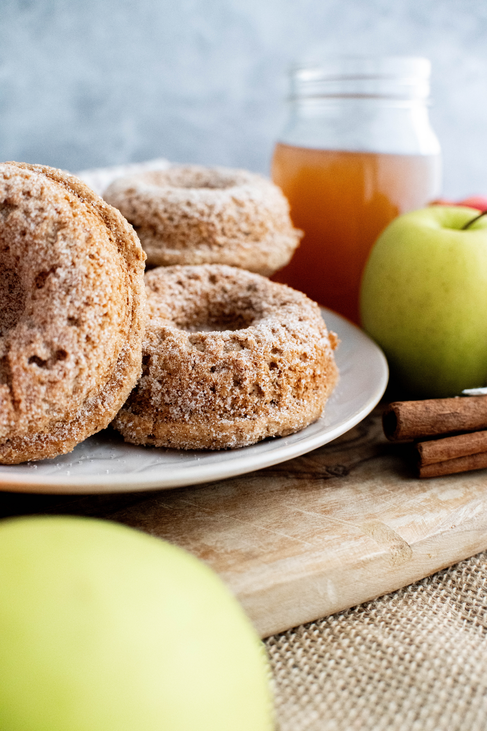 Round cream colored plate with a pile of sugar coated apple cider cake donuts.